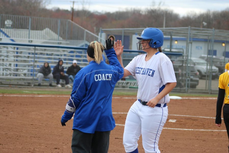 Coach Bridget Figmic giving Kailey Carrano a high five after reaching first base against OBrien Tech.